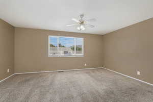 Carpeted spare room with baseboards and a ceiling fan