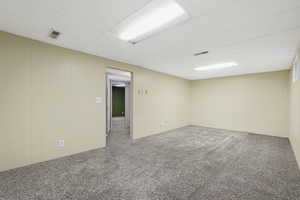 Carpeted spare room featuring a paneled ceiling