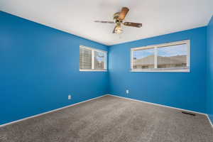 Carpeted spare room featuring ceiling fan and baseboards