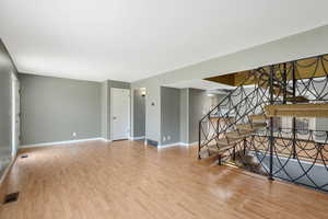 Empty room with stairway and wood finished floors
