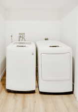 Washroom with light wood-style floors and washer and dryer