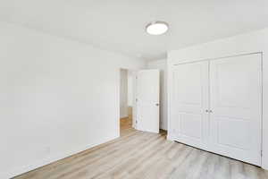 Unfurnished bedroom with light wood-style floors and a closet