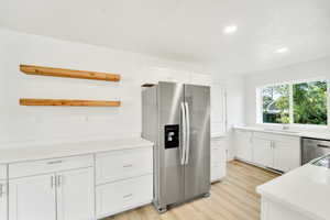 Kitchen with open shelves, stainless steel appliances, white cabinetry, light wood-type flooring, and recessed lighting