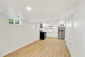 Kitchen featuring open shelves, stainless steel appliances, white cabinetry, light wood finished floors, and recessed lighting