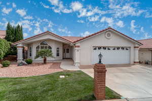 Mediterranean / spanish home with stucco siding, a tiled roof, driveway, a garage, and a front lawn