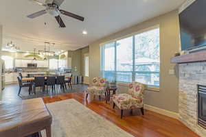 Living room with a fireplace, wood finished floors, recessed lighting, and ceiling fan