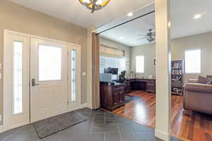 Foyer with dark tile patterned flooring, ceiling fan, and recessed lighting