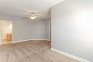 Large unfurnished bedroom with light colored carpet and ceiling fan