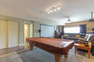 Recreation room / theater featuring billiards, Projector and screen, a textured ceiling, and wood finished floors