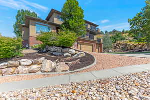 View of front of home featuring a balcony, brick siding, stucco siding, an attached garage, and concrete driveway