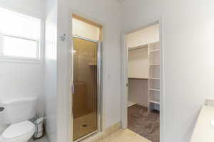 Bathroom with a stall shower, a walk in closet, tile patterned floors, and vanity
