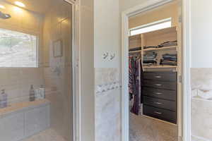Bathroom featuring a stall shower, tile walls, healthy amount of natural light, and a spacious closet
