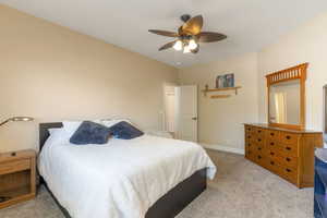 Carpeted bedroom featuring a ceiling fan and baseboards