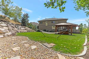 Rear view of house featuring a gazebo, hot-tub, and a yard