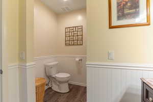 Bathroom with wainscoting, wood finished floors, vanity, and a decorative wall