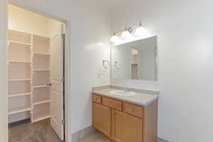 Bathroom with vanity and baseboards and walk-in closet