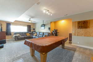 Recreation room with carpet flooring, billiards, a textured ceiling, ceiling fan, and wooden walls to dart board