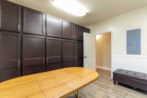 Laundry/Mudroom with electric panel, light wood-style floors, and wainscoting