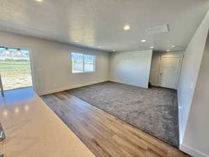 living room with recessed lighting, a textured ceiling, and wood finished floors