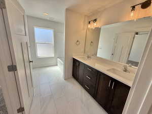 Bathroom with double vanity and marble look tile flooring
