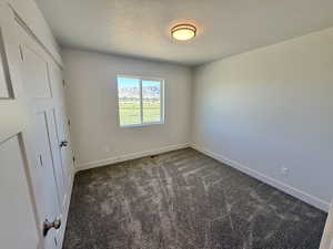 Unfurnished bedroom featuring dark carpet and a textured ceiling
