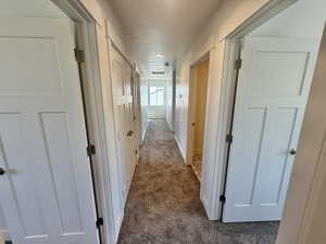 Hall featuring dark carpet and baseboards