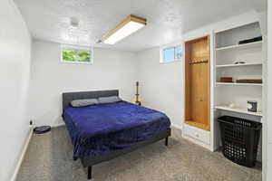 Carpeted bedroom featuring a textured ceiling and multiple windows