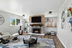 Living area with a textured ceiling, wood finished floors, and a fireplace
