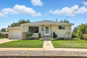 View of front facade with a garage, a front yard, concrete driveway, and a shingled roof