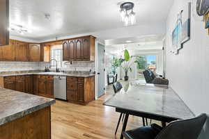 Kitchen featuring light wood-style floors, backsplash, stainless steel dishwasher, and a textured ceiling