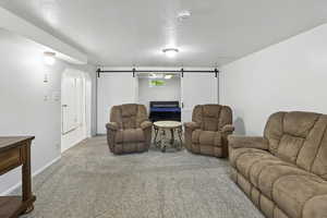 Carpeted living area with a textured ceiling and a barn door
