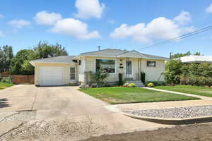 View of front facade with a garage, driveway, a front yard, and a shingled roof