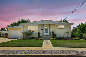 View of front of property featuring a garage, a front yard, driveway, and roof with shingles