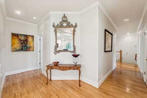 Corridor featuring ornamental molding, light wood finished floors, and recessed lighting