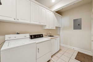 Laundry area featuring cabinet space, washing machine and clothes dryer, electric panel, light tile patterned floors, and recessed lighting