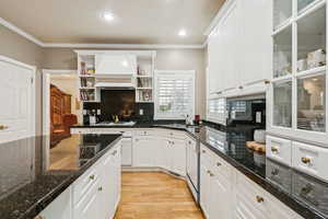 Kitchen featuring open shelves, light wood-type flooring, backsplash, white cabinetry, and ornamental molding