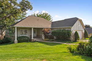 View of front facade featuring brick siding, a shingled roof, a garage, a front yard, and stucco siding