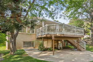 Back of property featuring brick siding, a patio, a wooden deck, and stairs