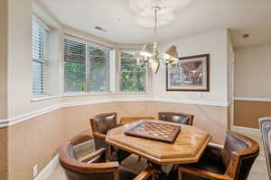 Dining room featuring a chandelier, a textured wall, and a textured ceiling