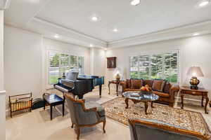 Living area with recessed lighting, ornamental molding, a raised ceiling, and light carpet