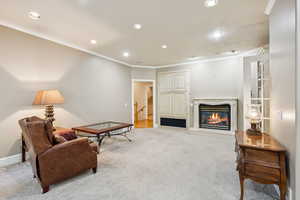 Living room featuring a fireplace, ornamental molding, light carpet, and recessed lighting
