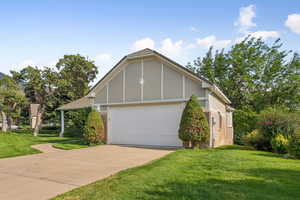 View of home's exterior featuring brick siding, a yard, driveway, and an attached garage