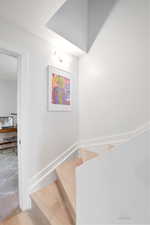 Stairway with wood finished floors and baseboards