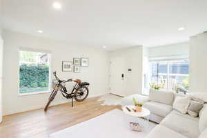 Living area with healthy amount of natural light, light wood-style floors, and recessed lighting
