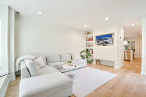 Living area featuring light wood-style flooring, recessed lighting, and built in shelves
