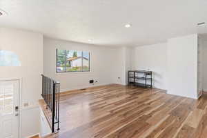 Large living room featuring light wood- floors, a textured ceiling, and recessed lighting