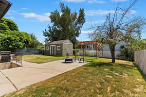 Fenced backyard with a large patio area, and fantastic shed. You can see the stairs to the basement entry to the left.