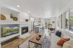 Living area featuring a glass covered fireplace, light wood-type flooring, recessed lighting, and a textured ceiling