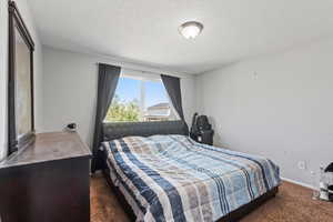 Bedroom featuring dark carpet and a textured ceiling