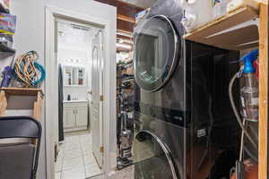 Washroom featuring stacked washing machine and dryer and light tile patterned floors